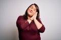 Beautiful brunette plus size woman wearing casual sweater over  white background sleeping tired dreaming and posing with Royalty Free Stock Photo