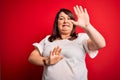 Beautiful brunette plus size woman wearing casual t-shirt over isolated red background afraid and terrified with fear expression Royalty Free Stock Photo