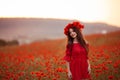 Beautiful brunette in red poppies field. Happy smiling teen girl portrait with wreath on head enjoying in poppy flowers nature bac Royalty Free Stock Photo