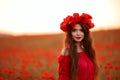 Beautiful brunette in red poppies field. Happy smiling teen girl portrait with wreath on head enjoying in poppy flowers nature Royalty Free Stock Photo