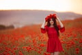 Beautiful brunette in red poppies field. Happy smiling teen girl portrait with wreath on head enjoying in poppy flowers nature Royalty Free Stock Photo