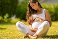 Beautiful pregnant woman sitting on the grass in her garden Royalty Free Stock Photo
