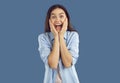 Beautiful brunette screams with joy and happiness holding her cheeks with her hands. Royalty Free Stock Photo