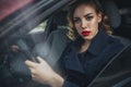 Beautiful brunette sexy spy agent killer or police woman in leather jacket and jeans with a gun in her hand driving a car after Royalty Free Stock Photo