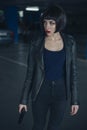 Beautiful brunette sexy spy agent killer or police woman in leather jacket and jeans with a gun in her hand running after Royalty Free Stock Photo