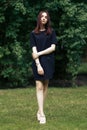 Beautiful brunette stylish girl posing with windy hair and confident look in city park in summer