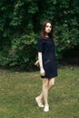 Beautiful brunette stylish girl posing with windy hair and confident look in city park in summer