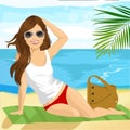 Beautiful brunette with sunglasses sunbathing on the beach sitting on a towel Royalty Free Stock Photo