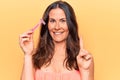 Beautiful brunette woman asking for depilation holding shaver razor over yellow background smiling with an idea or question