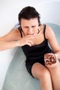 Beautiful brunette woman in black dress with a glass sitting alone in water-filled bath and crying. Royalty Free Stock Photo