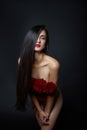 Beautiful brunette woman with a bouquet of red rose flowers in red corset. Long hair, nude slim body art portrait Royalty Free Stock Photo