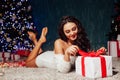Beautiful brunette woman at the Christmas tree with garland lights and gifts for the new year Royalty Free Stock Photo