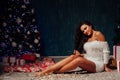Beautiful brunette woman at the Christmas tree with gifts of garland lights for the new year Royalty Free Stock Photo