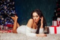 Beautiful fashionable brunette woman at the Christmas tree with gifts for the new year Royalty Free Stock Photo