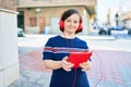 Beautiful brunette woman with down syndrome at the town on a sunny day using touchpad device listening to music wearing headphones Royalty Free Stock Photo