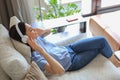 Beautiful brunette woman in earphones sitting on sofa listening to music with closed eyes. Royalty Free Stock Photo