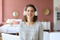 Beautiful brunette woman in earphones sitting on sofa listening to music with closed eyes Royalty Free Stock Photo