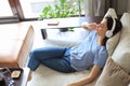 Beautiful brunette woman in earphones sitting on sofa listening to music with closed eyes. Royalty Free Stock Photo