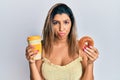 Beautiful brunette woman eating doughnut and drinking coffee depressed and worry for distress, crying angry and afraid Royalty Free Stock Photo