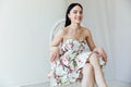 Beautiful brunette woman in floral dress sitting on chair