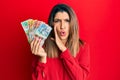 Beautiful brunette woman holding australian dollars hand on mouth telling secret rumor, whispering malicious talk conversation Royalty Free Stock Photo