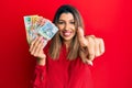 Beautiful brunette woman holding australian dollars pointing to you and the camera with fingers, smiling positive and cheerful Royalty Free Stock Photo
