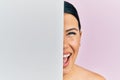 Beautiful brunette woman holding blank empty banner covering half face smiling and laughing hard out loud because funny crazy joke Royalty Free Stock Photo