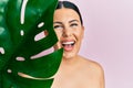 Beautiful brunette woman holding green plant leaf close to beautiful face smiling and laughing hard out loud because funny crazy Royalty Free Stock Photo