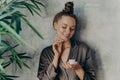 Beautiful brunette woman at home in silk brown pajama doing beauty procedures