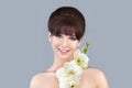 Beautiful brunette woman with perfect hairstyle. Model with smooth shiny hair and bangs holding white orchid flower Royalty Free Stock Photo