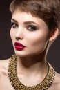 Beautiful brunette woman with perfect skin, bright makeup and gold jewelry. Beauty face. Royalty Free Stock Photo