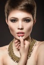 Beautiful brunette woman with perfect skin, bright makeup and gold jewelry. Beauty face. Royalty Free Stock Photo