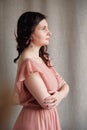 Beautiful brunette woman in a pink dress on a background of linen fabric. Copy, empty space for text Royalty Free Stock Photo