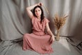 Beautiful brunette woman in a pink dress on a background of linen fabric. Copy, empty space for text Royalty Free Stock Photo