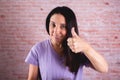 Beautiful brunette woman raising a thumb on a brick wall background Royalty Free Stock Photo