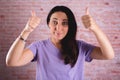 Beautiful brunette woman raising two thumbs on a brick wall background Royalty Free Stock Photo