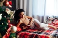 Beautiful woman reads a book on the bed near the Christmas tree New Year Royalty Free Stock Photo