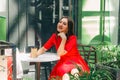 Beautiful brunette woman in red dress drinking coffee in a coffee shop Royalty Free Stock Photo