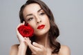 Beautiful brunette woman with red lipstick on lips. Close-up girl with rose. Royalty Free Stock Photo