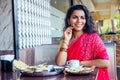 Beautiful brunette woman in red sari eating with appetite traditional thali with rise,curd,dal in Goa restaurant and Royalty Free Stock Photo