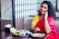 Beautiful brunette woman in red sari eating with appetite traditional thali wirh rise,curd,dal in Goa restaurant masala Royalty Free Stock Photo