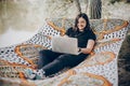 Beautiful brunette woman relaxing on hammock outdoors near lake in the forest, freelancer working in the park while resting in Royalty Free Stock Photo