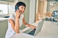 Beautiful brunette woman with short hair at home using computer laptop speaking on the phone Royalty Free Stock Photo