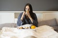 Beautiful brunette woman sitting on the bed,holding tea cup and eating breakfast Royalty Free Stock Photo