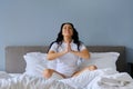 Beautiful brunette woman sitting in white bed in lotus position Royalty Free Stock Photo