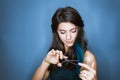 Beautiful brunette woman with a smile cutting long hair with scissors on a blue Royalty Free Stock Photo