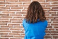 Beautiful brunette woman standing over bricks wall standing backwards looking away with crossed arms Royalty Free Stock Photo