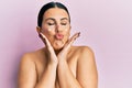 Beautiful brunette woman standing topless wearing face cream looking at the camera blowing a kiss being lovely and sexy Royalty Free Stock Photo