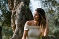 Beautiful brunette woman touching her long hair. She sits in a park on green grass. Royalty Free Stock Photo