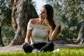 Beautiful brunette woman touching her long hair. She sits in a park on green grass. Royalty Free Stock Photo